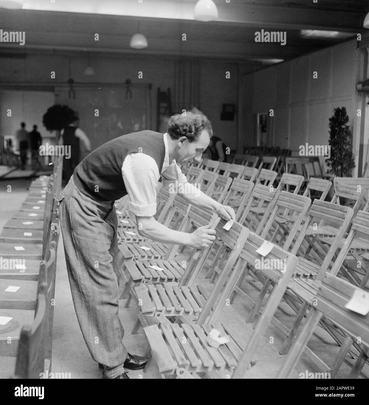 Usine de cigares du 50ème anniversaire Karel i Eindhoven Man attache des étiquettes aux chaises pliantes Date: 1 janvier 1950 lieu: Eindhoven mots clés: Usines, outils, chaises, industrie du tabac Banque D'Images