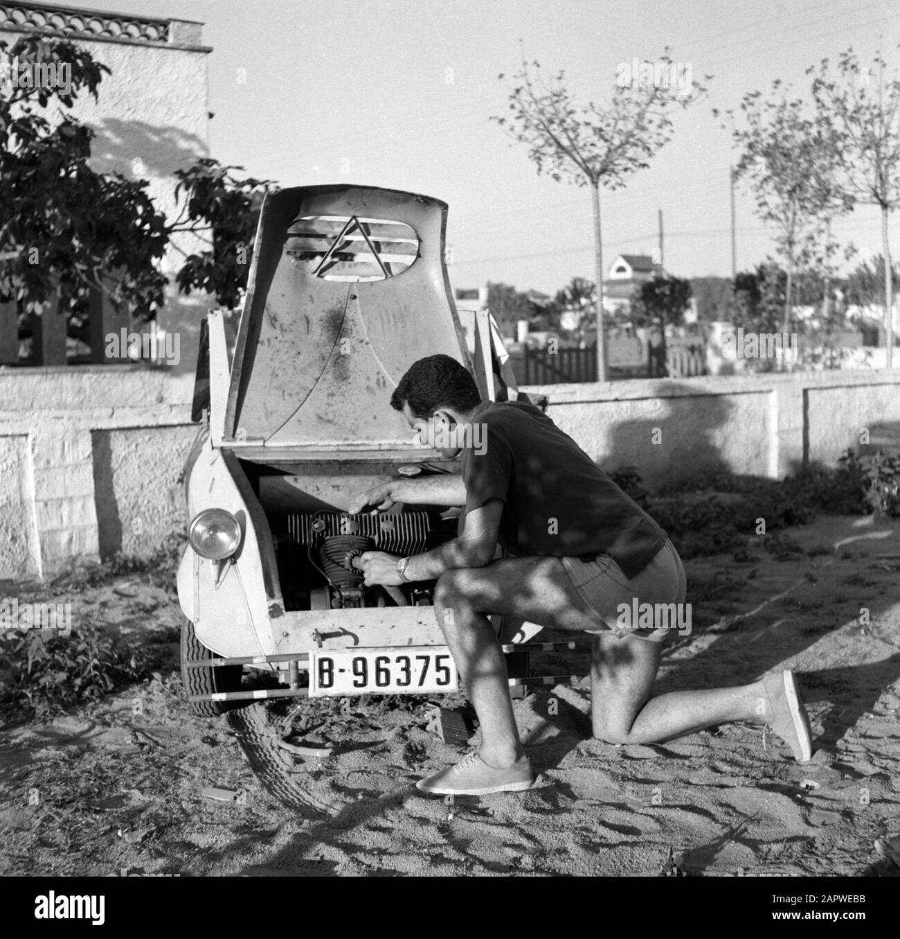 Voitures anciennes en Espagne l'homme s'agenouille avant le capot ouvert d'un Voisin et répare la voiture Date: 1958 lieu: Espagne mots clés: Voitures, autochtones, réparations Banque D'Images