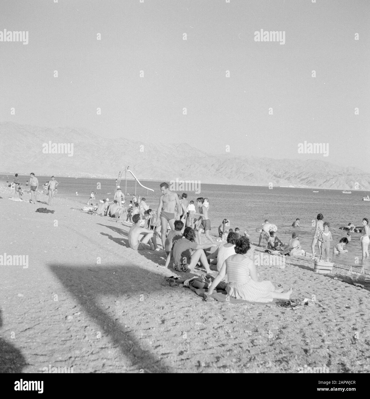 Personnes sur la plage près d'Eilat surplombant le golfe d'Aqaba et les montagnes voisines Date : 1 janvier 1963 lieu : Eilat, Golfe d'Aqaba, Israël mots clés : baignoires, montagnes, plages Banque D'Images