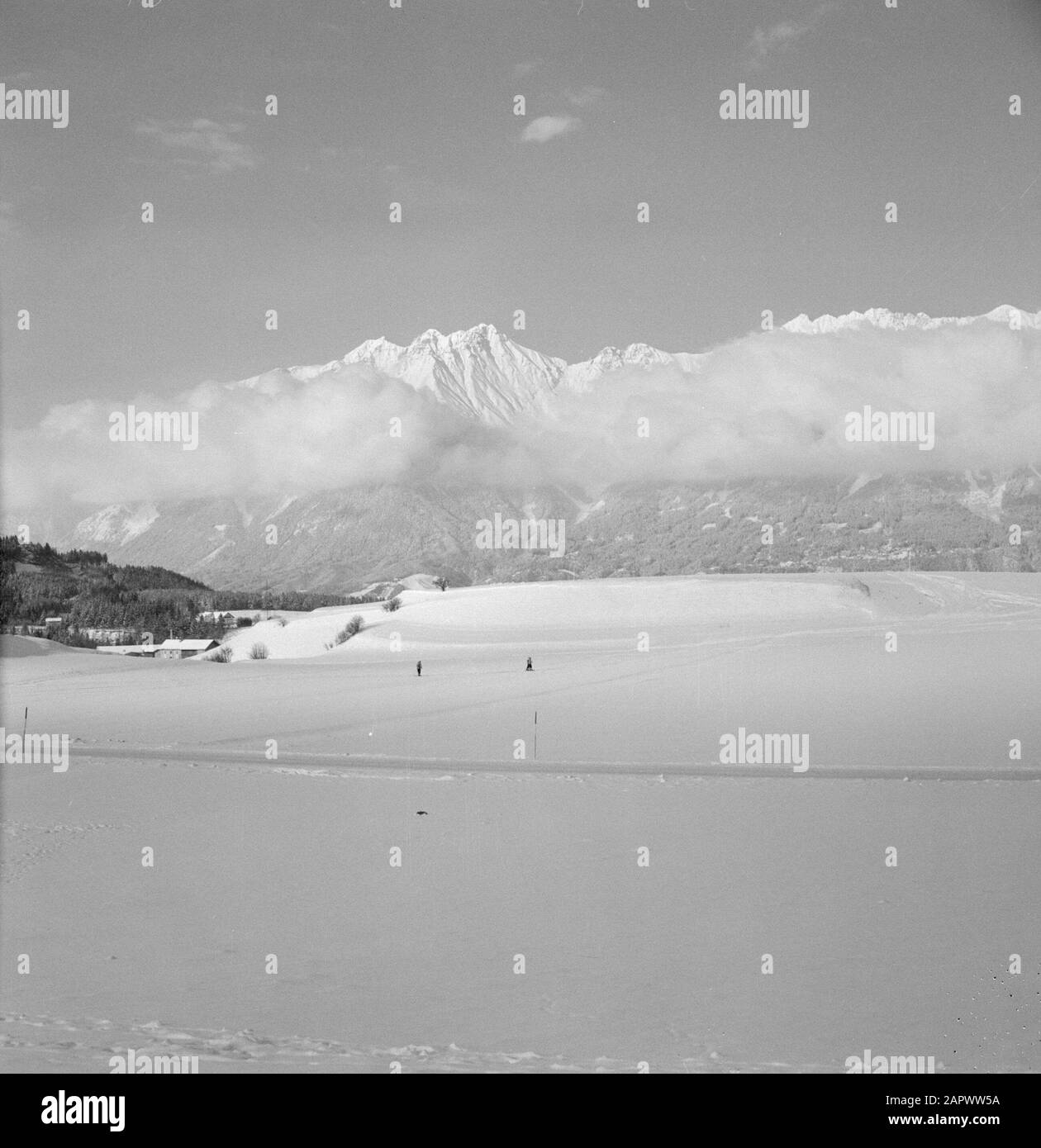 Hiver au Tirol Nordkette avec des nuages bas suspendus avec au premier plan ski de fond à Igls Date: Janvier 1960 lieu: Igls, Autriche, Tyrol mots clés: Montagnes, villages, paysages, ski de fond, panoramas, neige, hiver, sports d'hiver, nuages Banque D'Images