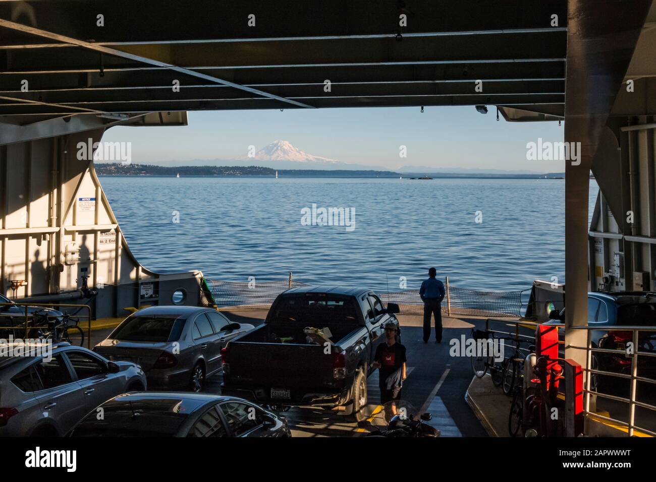 Un homme se tient sur la terrasse d'un ferry de l'État de Washington en regardant le paysage. Banque D'Images