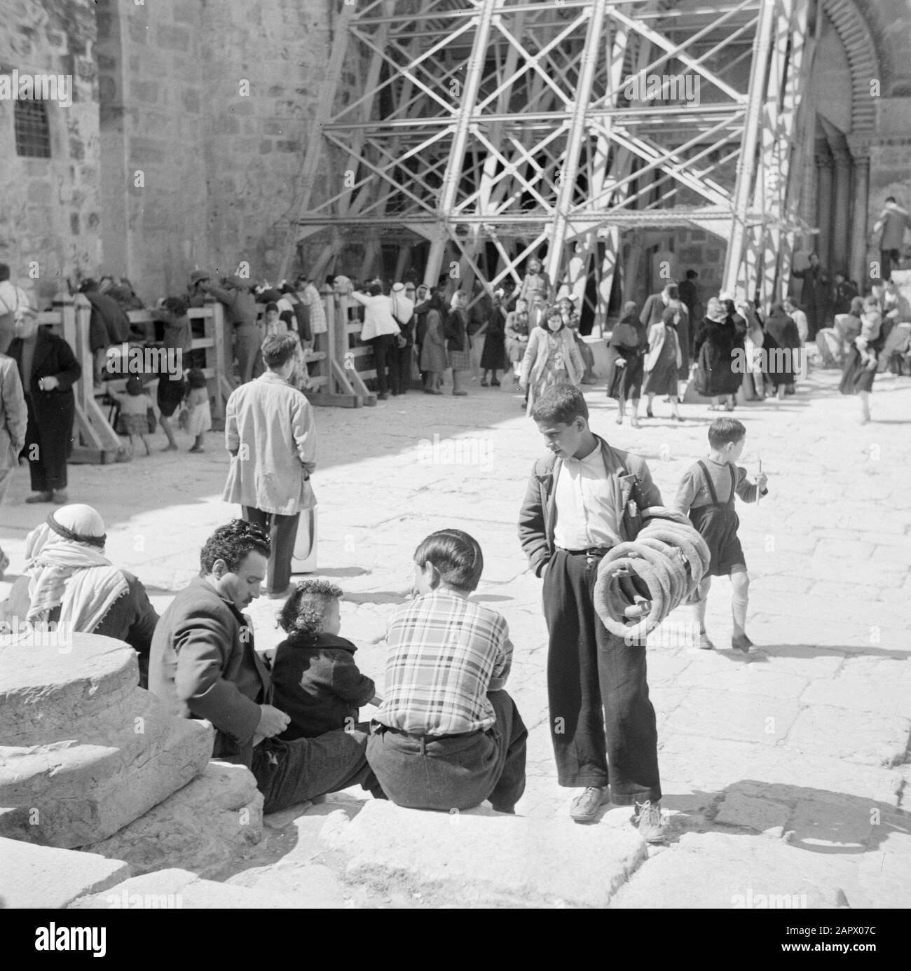 Moyen-Orient 1950-1955 : Célébration De Pâques À Jérusalem. Les croyants à l'échafaudage à l'entrée de l'annotation de l'église Sainte-Tombeau: Ceux qui n'ont pas de carte d'entrée sont séparés derrière une clôture de ceux qui le font. Au premier plan, un boulanger avec des pains arabes ronds. ' Au moment de l'enregistrement était Jérusalem en Jordanie Date: 1950 lieu: Palestine, Jérusalem, Jordanie mots clés: Boulangers, croyants, églises, échafaudage Banque D'Images