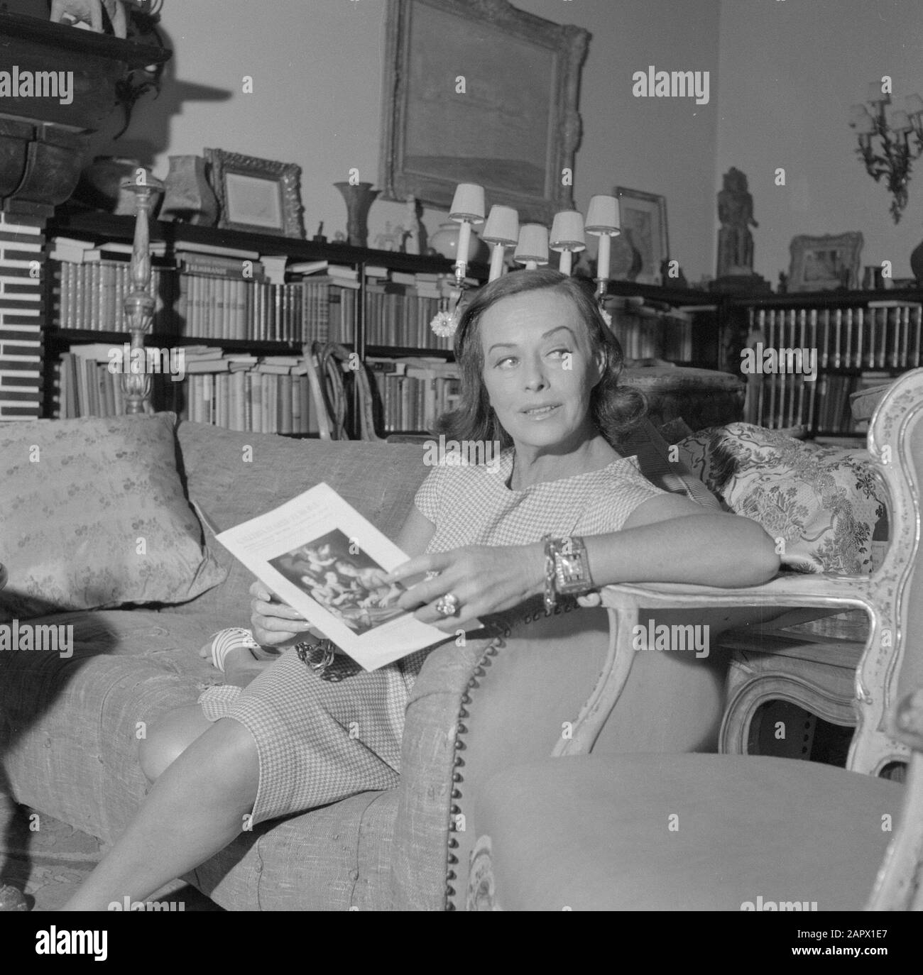 Visite de l'auteur allemand Erich Maria Remarque et de l'actrice américaine Paulette Goddard dans leur villa à Porto Ronco, Suisse Paulette Goddard dans le salon de la villa à Porto Ronco avec un livret Date: Octobre 1961 lieu: Lac majeur, Suisse mots clés: Acteurs, intérieurs, maisons Nom personnel: Goddard, Paulette Banque D'Images