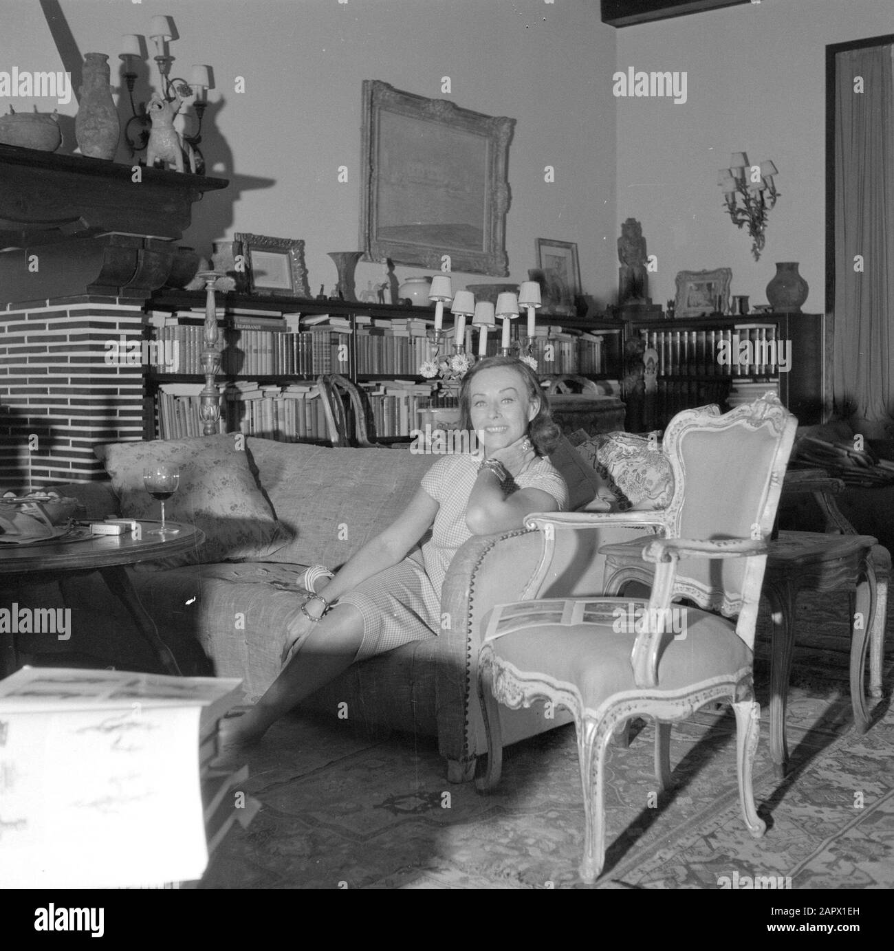 Visite de l'auteur allemand Erich Maria Remarque et de l'actrice américaine Paulette Goddard dans leur villa à Porto Ronco, Suisse Paulette Goddard en conversation, assis sur le canapé dans le salon de la villa à Porto Ronco Date: Octobre 1961 lieu: Lac majeur, Suisse mots clés: Acteurs, intérieurs, maisons Nom personnel: Goddard, Paulette Banque D'Images