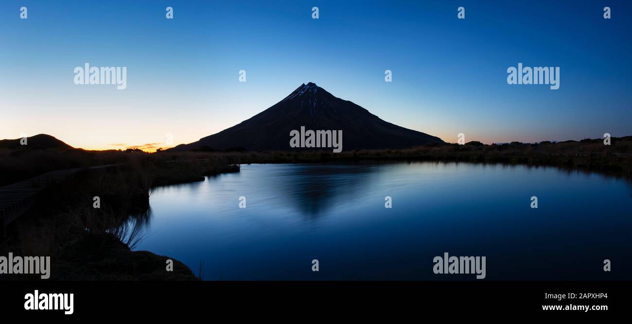 Le majestueux Mont Taranaki se reflète dans l'eau claire du tarn de Pouakai au lever du soleil Banque D'Images