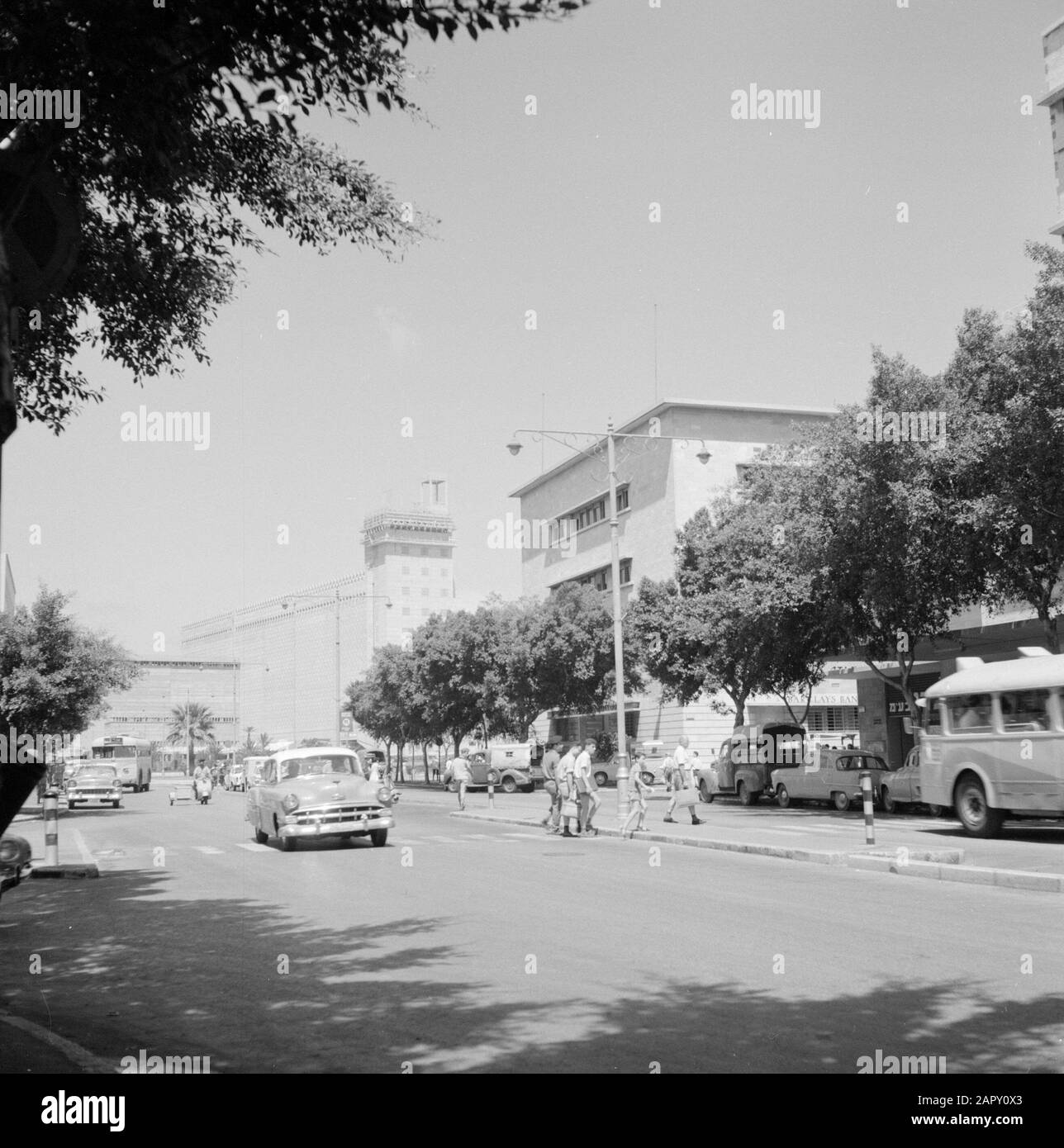 Israël 1964-1965: Haifa, Street images Road with City traffic, arbres and Apartment blocks, in the Middle Street lights and in the background 'agon grain silo' Date: 1964 lieu: Haifa, Israel mots clés: Voitures, arbres, immeubles d'appartements, ombres, silos, images de rues, lumières de rues, piétons, routes Banque D'Images