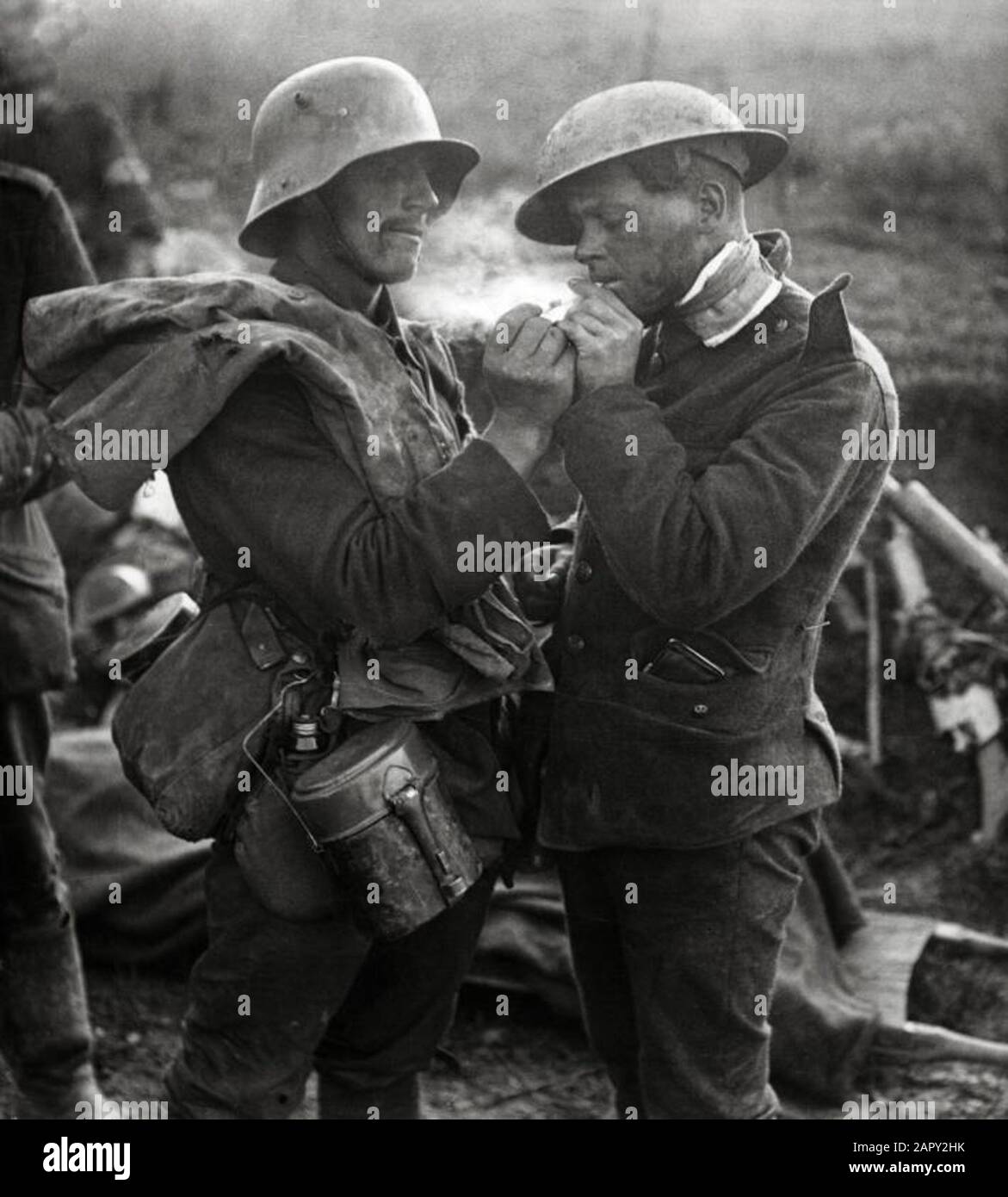 Un prisonnier de guerre allemand donne à un soldat anglais blessé, Tommy, un feu pour éclairer une cigarette pendant la première Guerre mondiale, lieu et année inconnus. Banque D'Images