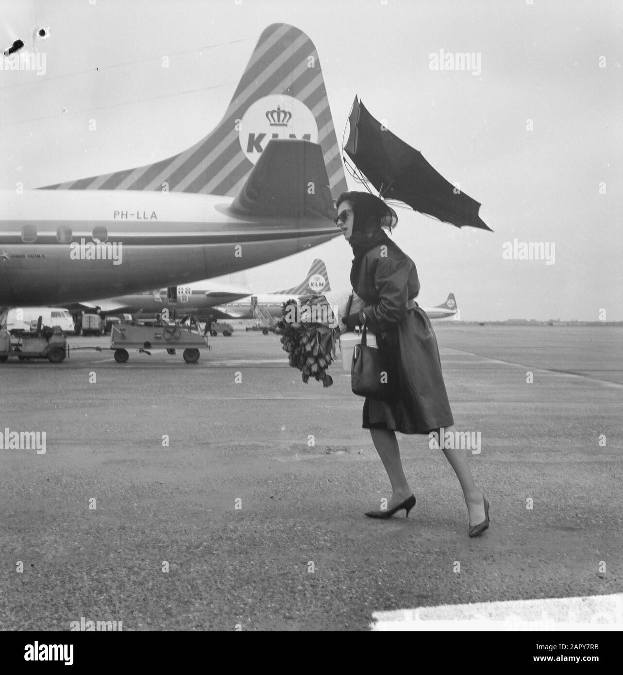 Airport Woman avec grand bouquet de fleurs. Son parapluie est détruit par  le vent violent] Date: 15 avril 1963 lieu: Schiphol mots clés: Fleurs,  parapluies, avions, aéroports Photo Stock - Alamy