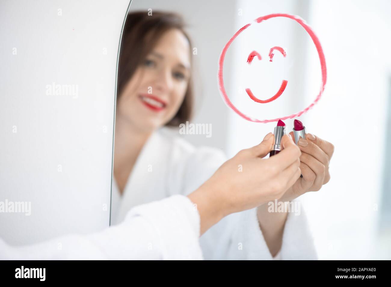 Main de jolie jeune femme gaie dans peignoir dessin visage avec sourire Banque D'Images