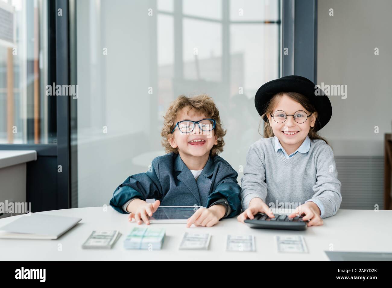 Deux petits comptables heureux avec tablette et calculatrice comptant de l'argent Banque D'Images