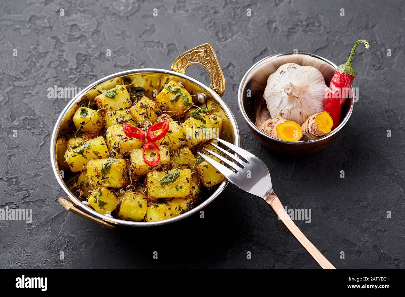 Aloo Methi en cuivre kadai, bol à fond d'ardoise sombre. Aloo Methi est un plat de cuisine indienne avec pommes de terre, Fenugrec et épices. Cuisine Indienne. Banque D'Images