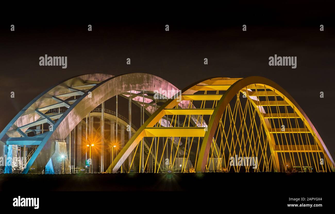 Ponts dans une ville avec de grandes arches jaunes et blanches en haut la nuit Banque D'Images