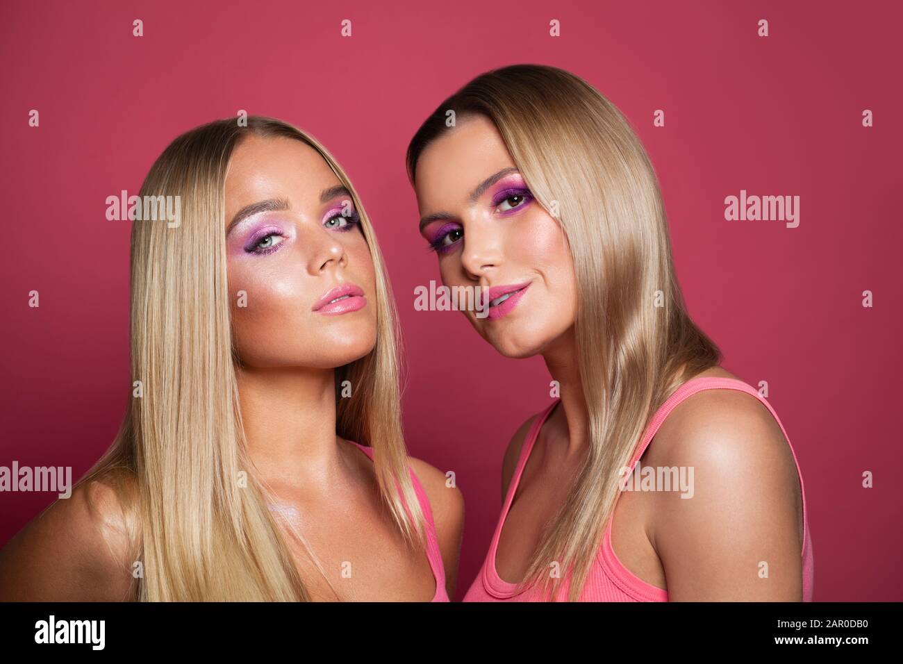 Portrait de beauté de mode de deux modèles de femmes magnifiques avec maquillage à la mode et cheveux blonds sur fond rose Banque D'Images