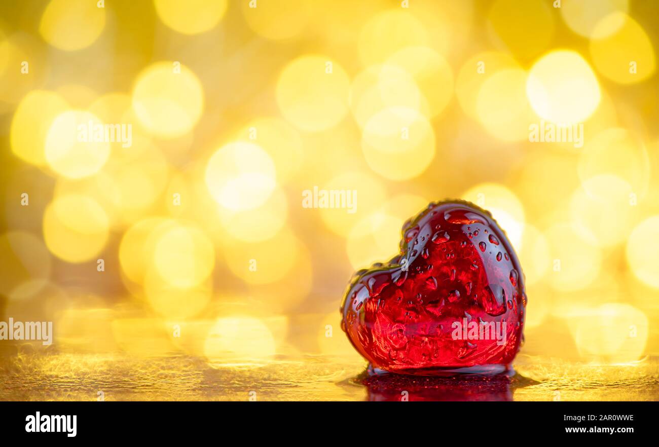 cœur rouge transparent dans des gouttes d'eau sur un fond doré avec bokeh. fond d'amour. saint valentin Banque D'Images