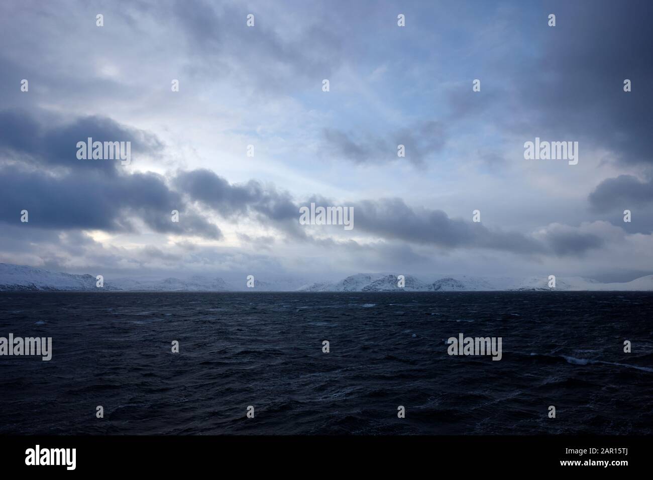 faites une pause dans les nuages au-dessus de la côte arctique norvégienne enneigée Banque D'Images