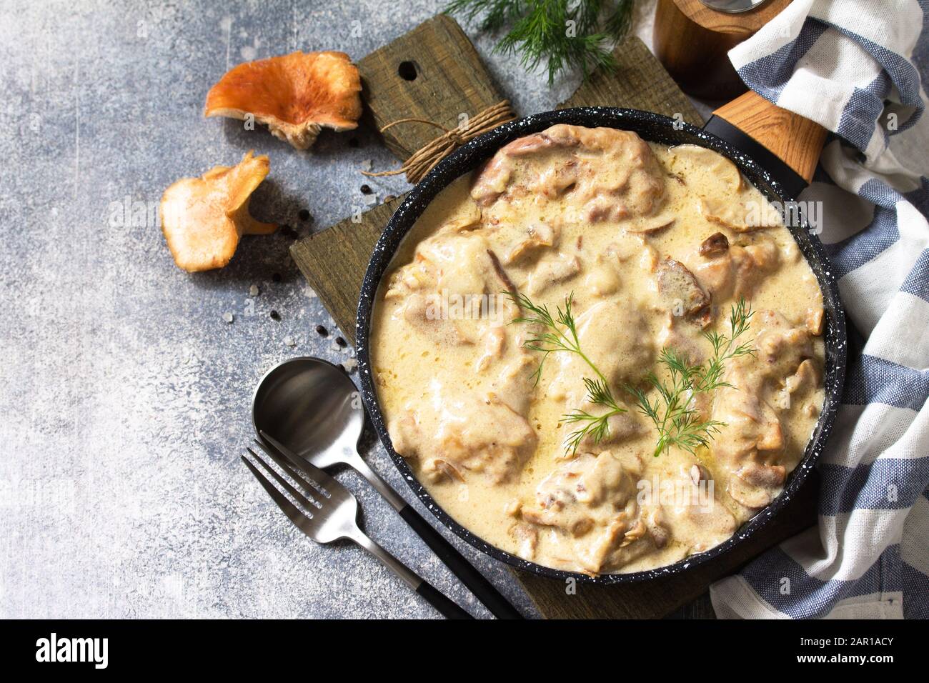 Fricasse - Cuisine Française. Poulet cuit dans une sauce crémeuse aux champignons dans une poêle sur fond de pierre légère. Espace de copie. Banque D'Images