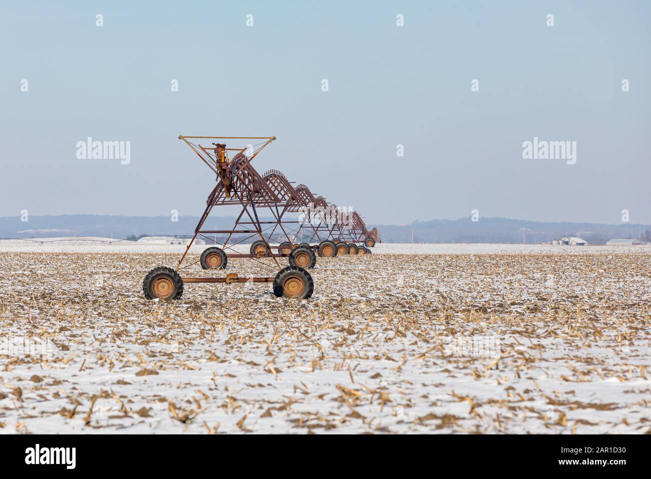 L'ancien système d'irrigation à pivot central rouillé est inactif dans le champ de maïs récolté couvert de neige en hiver. Concept d'entretien, de réparation et de maintenance Banque D'Images