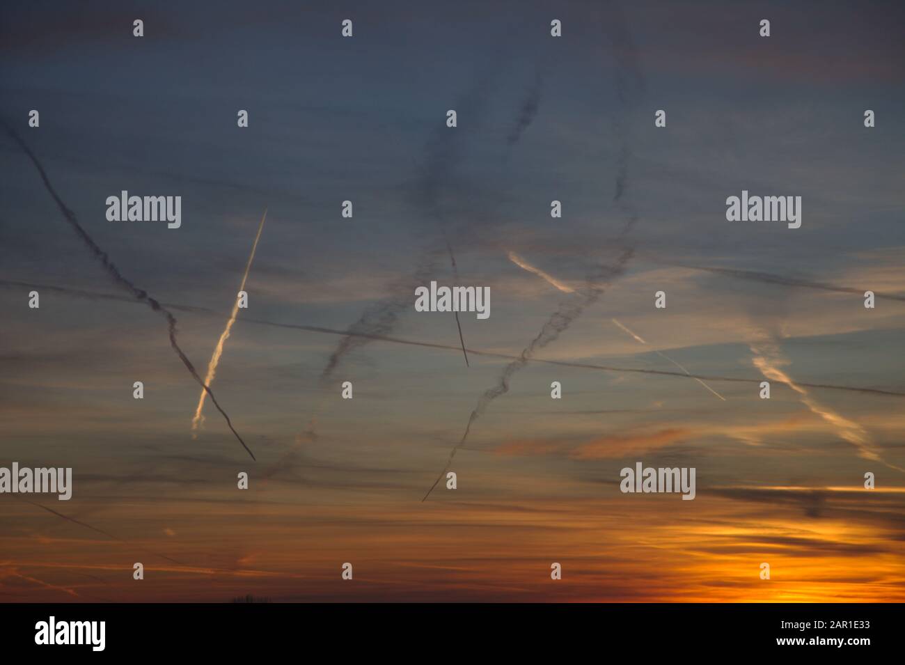 Pistes de vapeur d'avion montrant dans un ciel rouge au coucher du soleil. Frison Oriental. Allemagne Banque D'Images