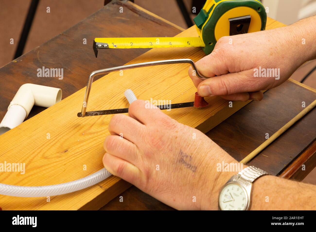 Une scie à hack junior est utilisée pour couper un petit morceau de tubulure en plastique Banque D'Images