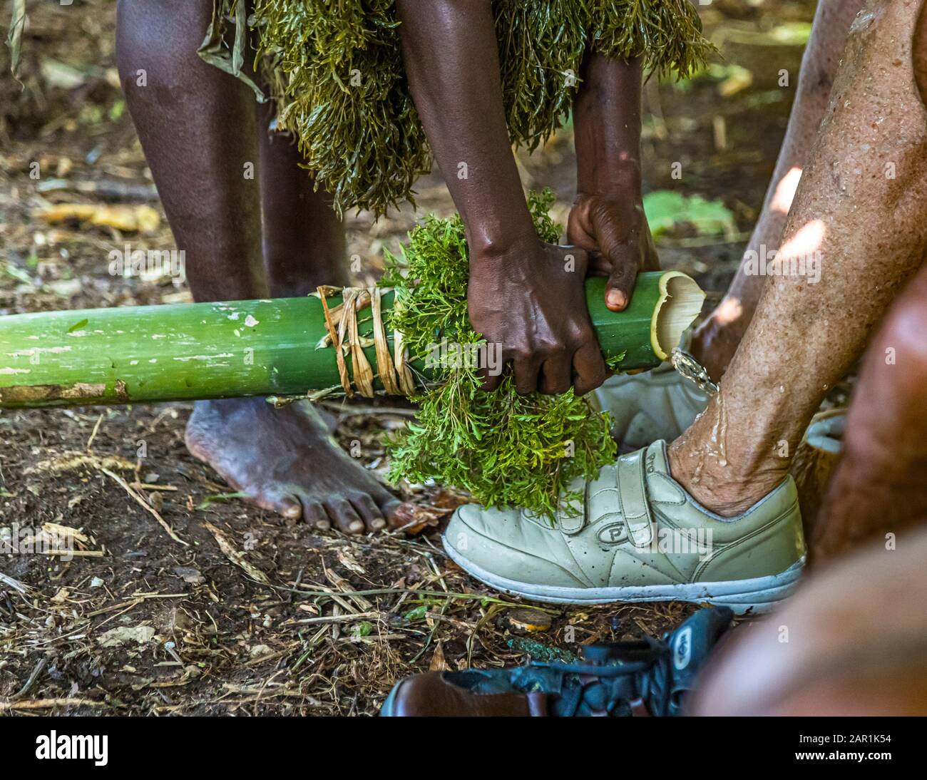 Les nouveaux arrivants à Bougainville sont accueillis de façon inhabituelle. Avec l'eau d'une canne en bambou, les pieds sont lavés au baptême de l'île. Le baptême de l'île comme bénédiction par les autochtones à Bougainville, Papouasie-Nouvelle-Guinée Banque D'Images