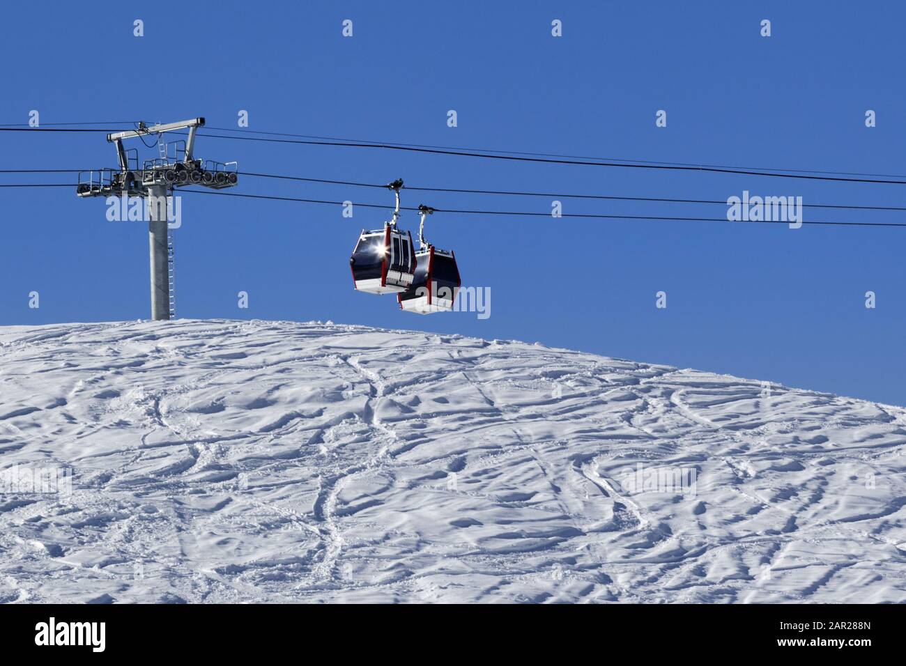 Télécabine, piste de ski hors piste avec trace de skis et de snowboards. Haute montagne d'hiver et ciel bleu clair en journée ensoleillée. Banque D'Images