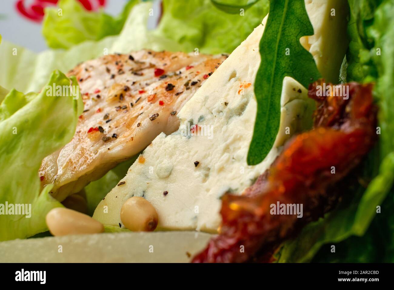 Macro photo de salade avec dinde rôtie, tomate séchée, gorgonzola, poire en conserve et noix de pin Banque D'Images