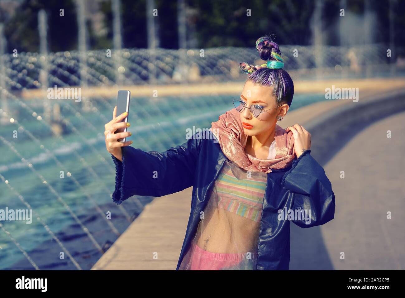 Cool funky hipster jeune fille influenceur de mode avec des cheveux fous et style avant-garde prenant selfie sur la rue Banque D'Images