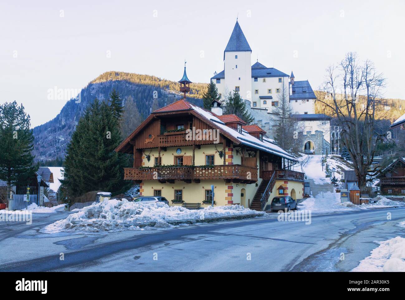 MAUTERNDORF, AUTRICHE, 21 JANVIER. 2020: Château de Mauterndorf avec une maison traditionnelle en bois au premier plan en hiver. Image horizontale. Banque D'Images