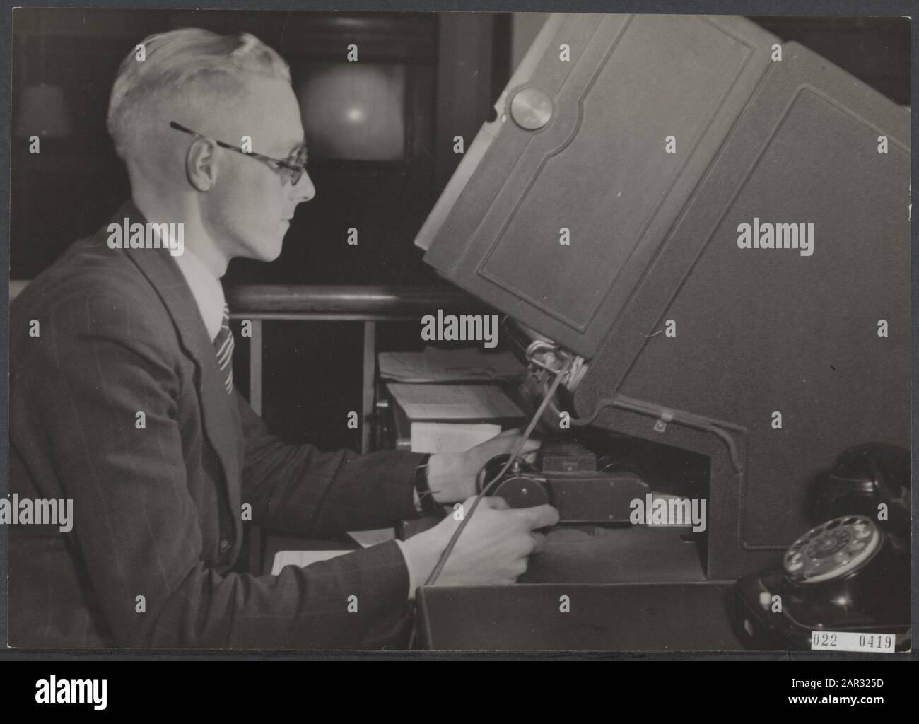 Préparatifs des premières élections de la deuxième chambre après la guerre. Les bonnes élections sont fondées sur des registres de population fiables. De par la nature de la question, beaucoup de choses ont changé ici au cours des cinq dernières années. Sur la base d'un film étroit sur lequel la plupart des données des registres de population avaient déjà été enregistrées avant la guerre, les carthotiques sont remis en ordre. Un fonctionnaire de l'appareil ingénieux avec lequel les données du film sont reproduites en taille réelle Date: 6 novembre 1945 lieu: Amsterdam, Noord-Holland mots clés: Officiels, dispositifs, microfilms, second Wor Banque D'Images