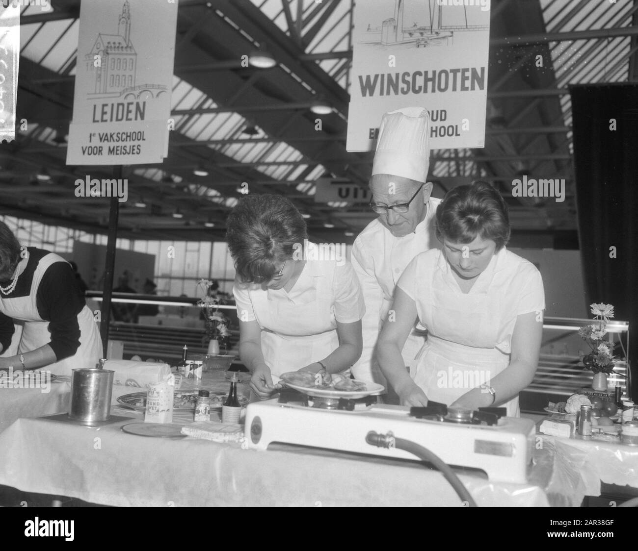 École familiale 1965 filles préparant des plats sous l'œil attentif du chef H. Ecksteen Date: 18 novembre 1965 mots clés: Démonstrations, ménages, cuisiniers, cuisine, filles, préparation de nourriture Nom personnel: Ecksteen, H. Banque D'Images