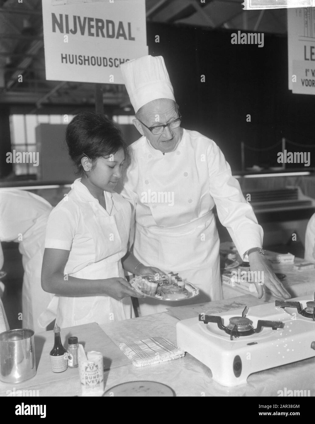 École familiale 1965 fille préparant des plats sous l'œil attentif du chef H. Ecksteen Date: 18 novembre 1965 mots clés: Démonstrations, ménages, cuisiniers, cuisine, filles, préparation de nourriture Nom personnel: Ecksteen, H. Banque D'Images