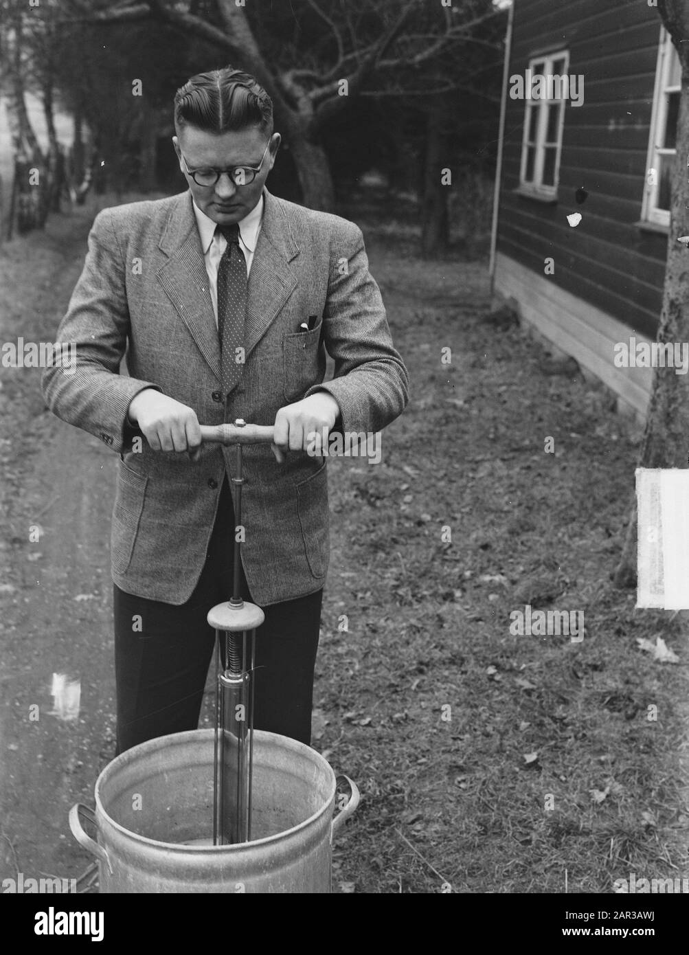 E. Koose du hameau de Joppe (près de Gorssel) a inventé un appareil avec lequel un linge normal peut être fait en 5 minutes. L'utilisation de cette solution coûte moins de savon et moins d'effort. Cette machine, qui ressemble à une pompe à vélo, n'est plus battue par l'eau savonneuse, mais le savon est battu par la cire. L'inventeur avec la machine à laver à pompe Date: 30 janvier 1951 lieu: Gueldre, Joppe mots clés: Ménage, inventeurs, inventions, lave-linge Nom: Cours, E. Banque D'Images