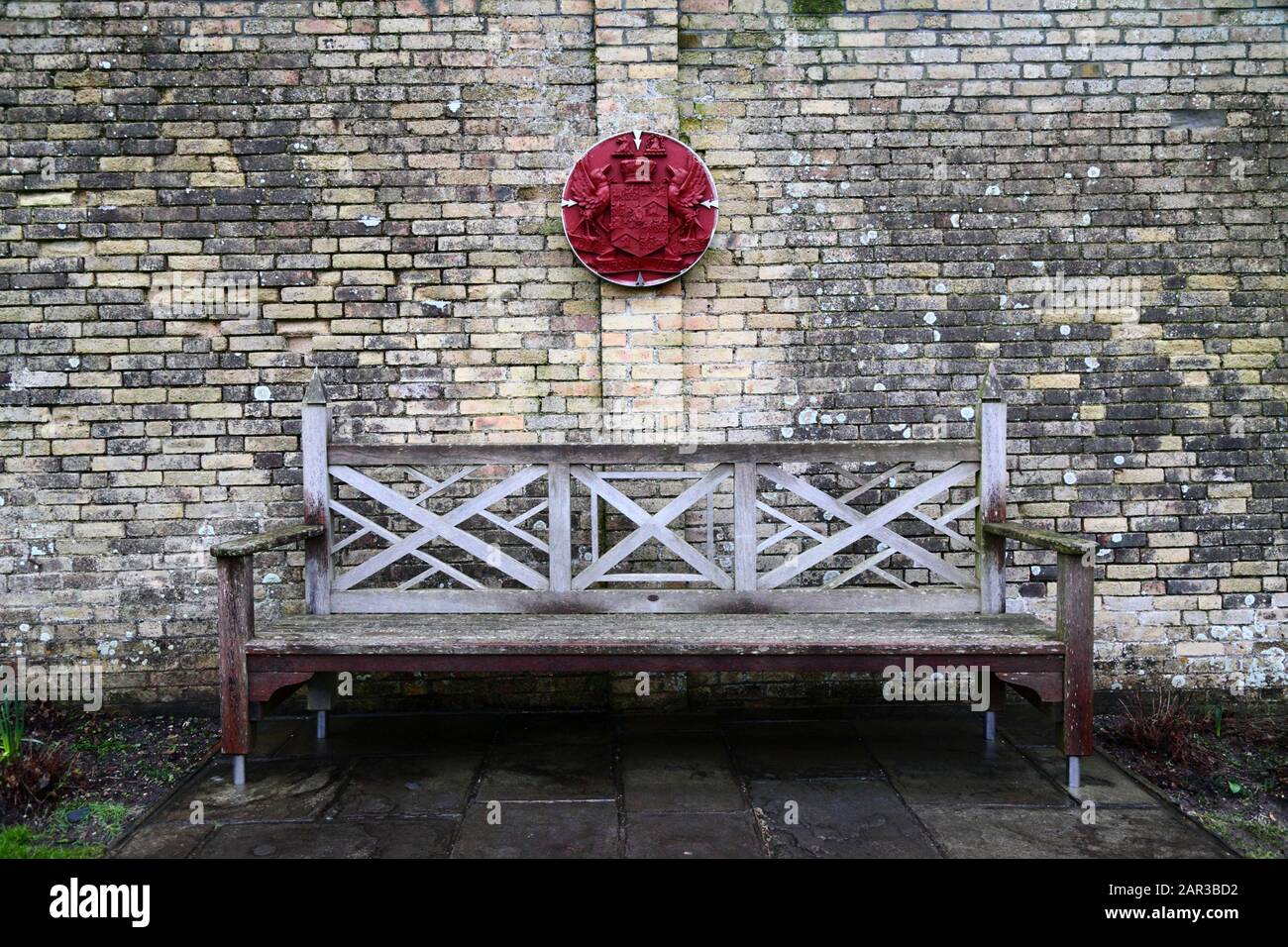 Banc en bois et armoiries du comte de Dunraven sur le mur dans des jardins qui faisaient autrefois partie du domaine du château de Dunraven, South Glamourgan, Pays de Galles, Royaume-Uni Banque D'Images