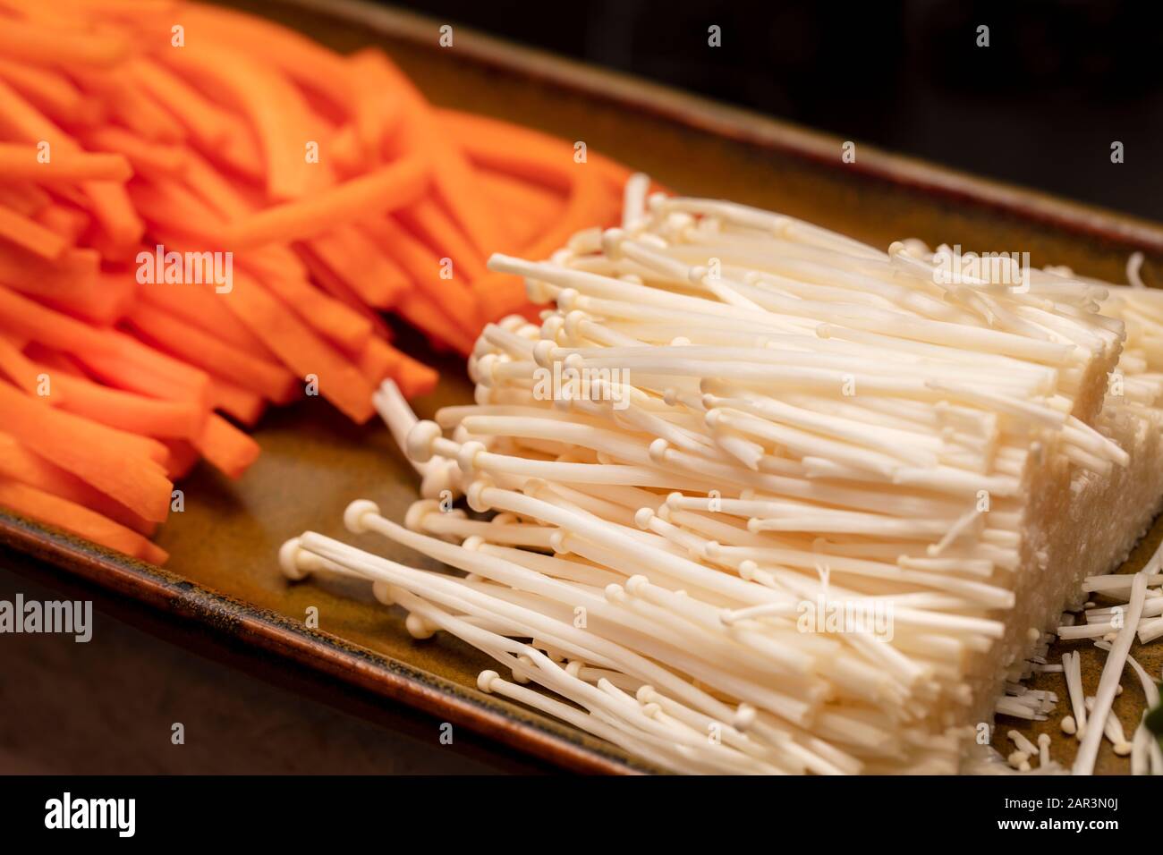 Les carottes julienne et les champignons énokitake sont coupés et utilisés pour fabriquer des sushis Banque D'Images