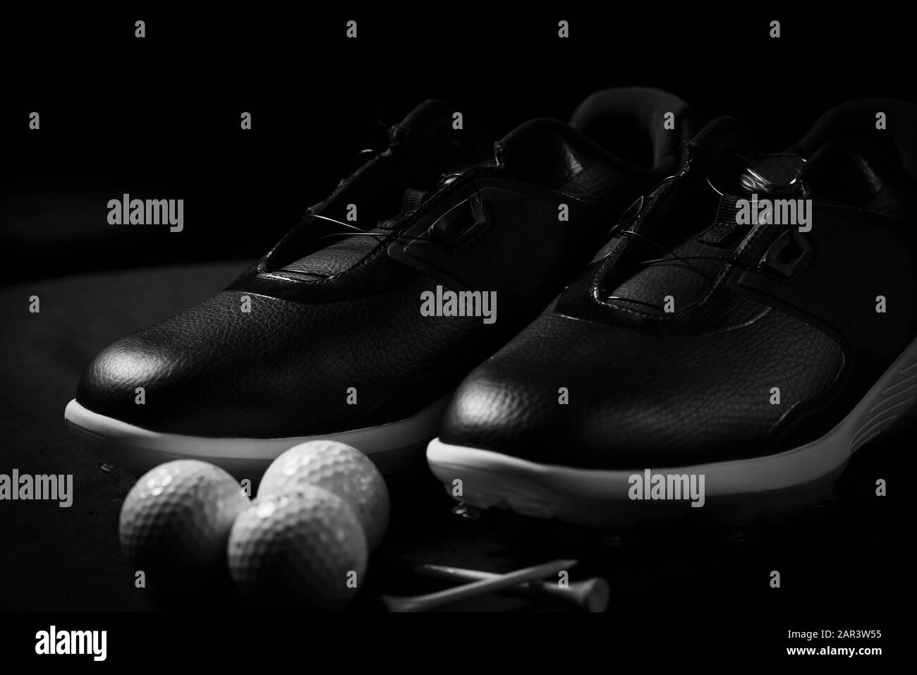 Chaussures de golf, balles et tee isolés sur fond noir. Banque D'Images
