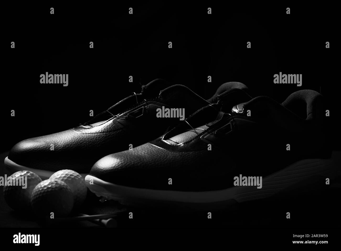 Chaussures de golf, balles et tee isolés sur fond noir. Banque D'Images