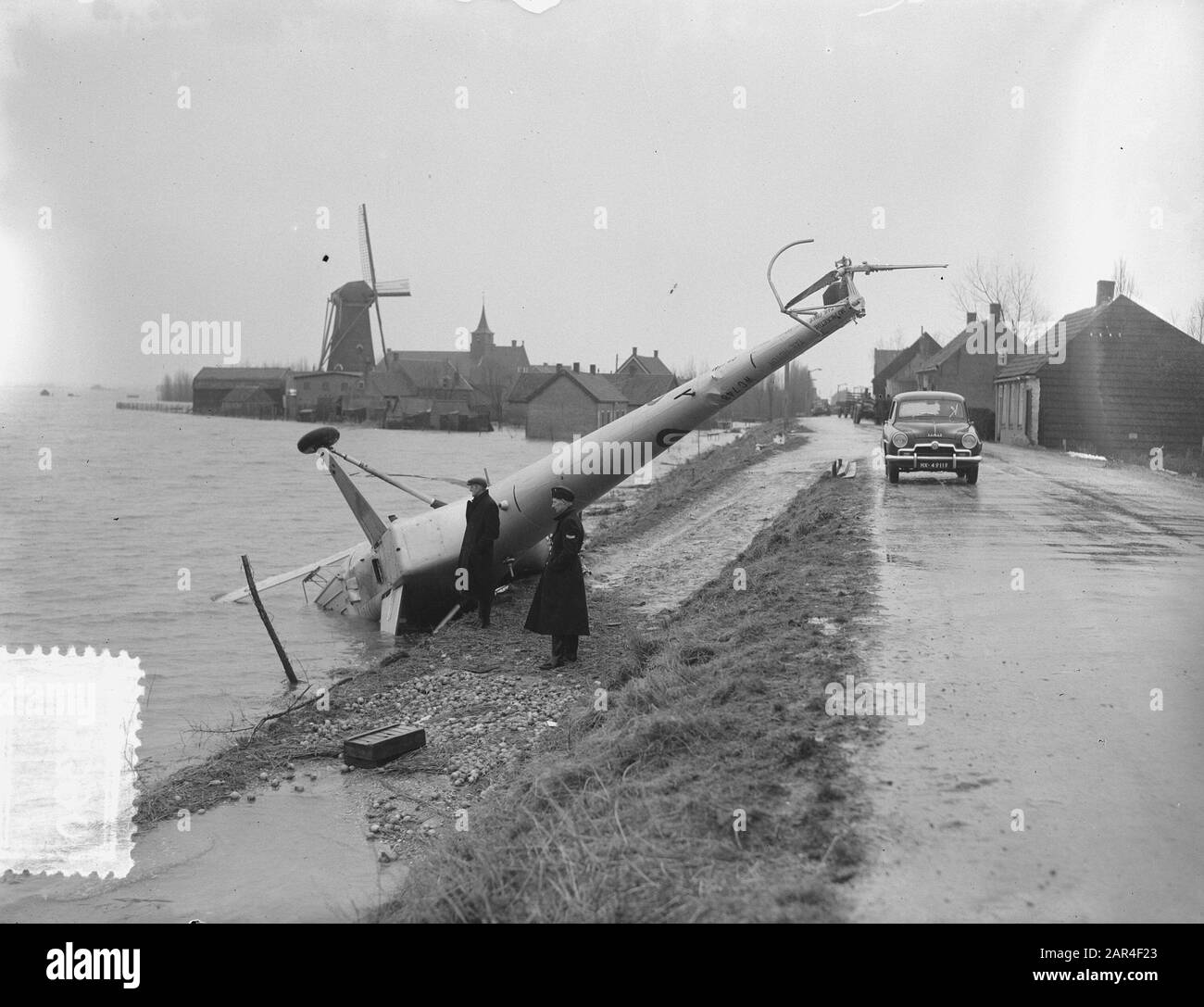 L'hélicoptère anglais, un Sikorsky, s'est écrasé à Achthuizen (Hollande du Sud) pendant le secours après la catastrophe d'inondation. [En arrière-plan Moulin à maïs visible, nommé Windlust. Moulin à pierre rond, construit en 1852] Date : 10 février 1953 lieu : huit maisons mots clés : hélicoptères, aviation, moulins à vent, accidents, inondation Banque D'Images