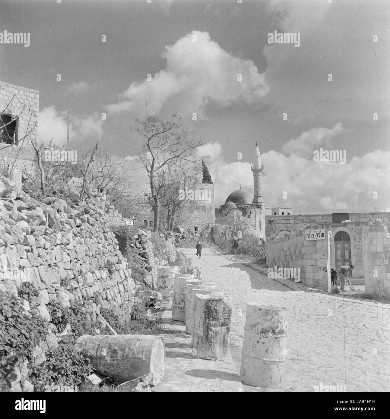 Israël 1948-1949 vue sur le village avec une mosquée, un minaret et quelques maisons et murs le long d'une route avec des barils d'essence vides comme marquage de route Date: 1948 lieu: Israël mots clés: Architecture, images de village, emballage, mosquées, clôtures Banque D'Images