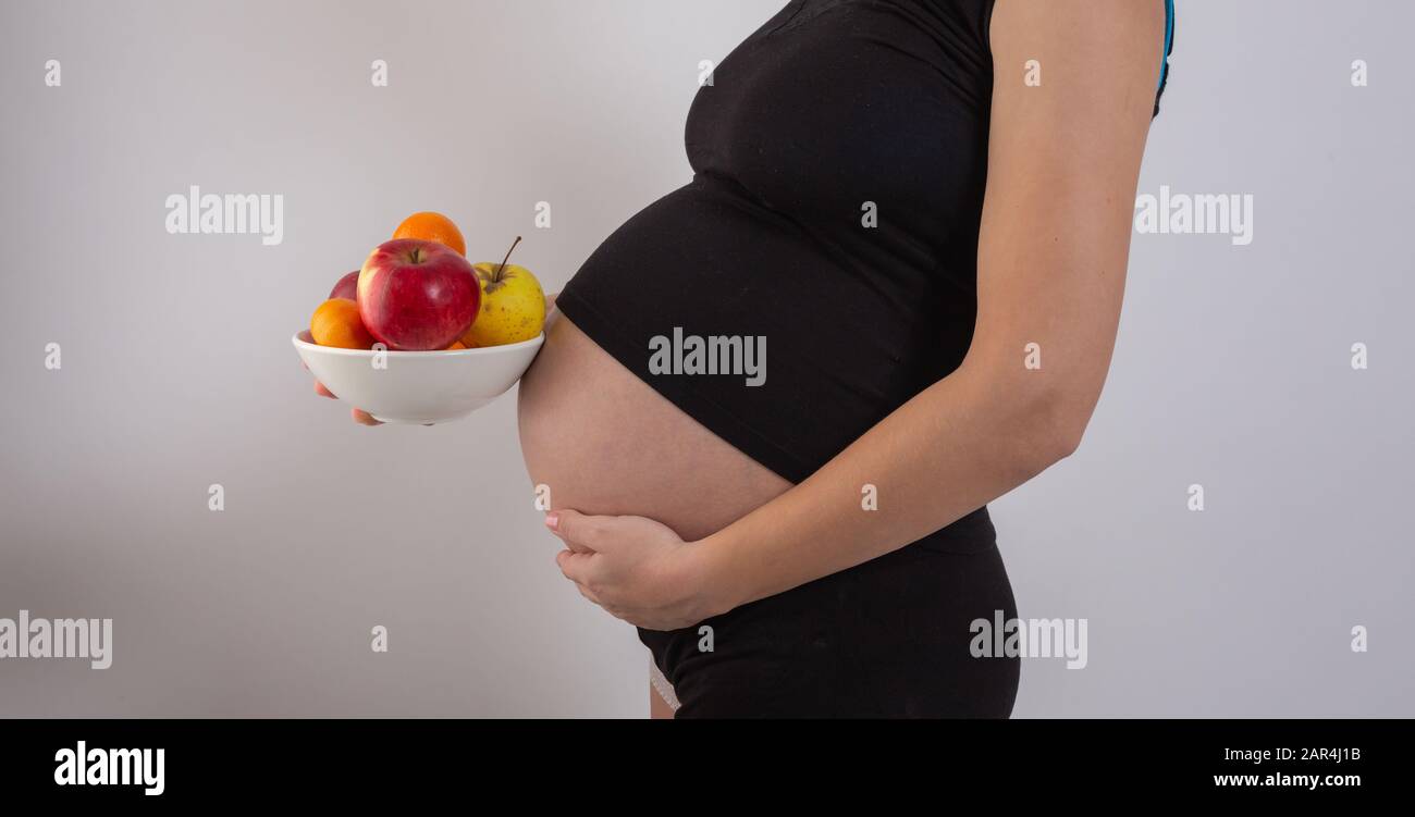 Grossesse et nutrition organique saine. La femme enceinte détient des fruits de vitamine frais, de l'espace libre. Placer pour le texte. Concept d'attente et de santé. Banque D'Images