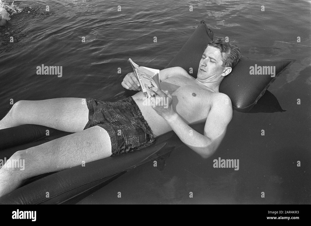 Vacances un homme sur un lit d'avion lit un livre Date: 3 juillet 1967 mots clés: Livres, lecture, hommes, loisirs, vacances, eau Banque D'Images