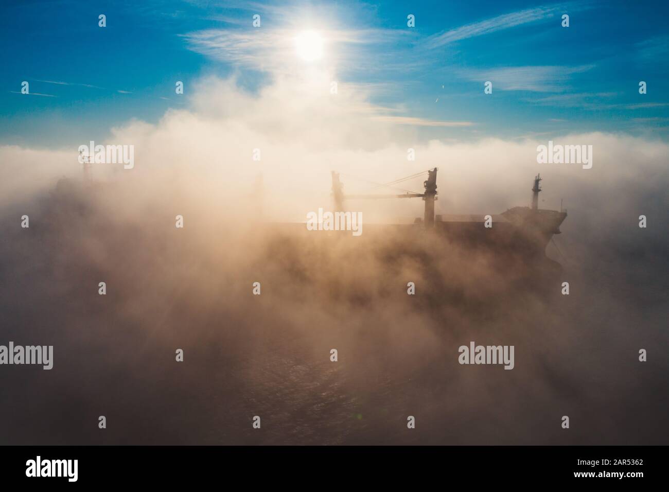 Grues de navire de charge et de silhouettes en brouillard de mer, bateau grue travaillant pour la livraison des conteneurs de livraison. Banque D'Images