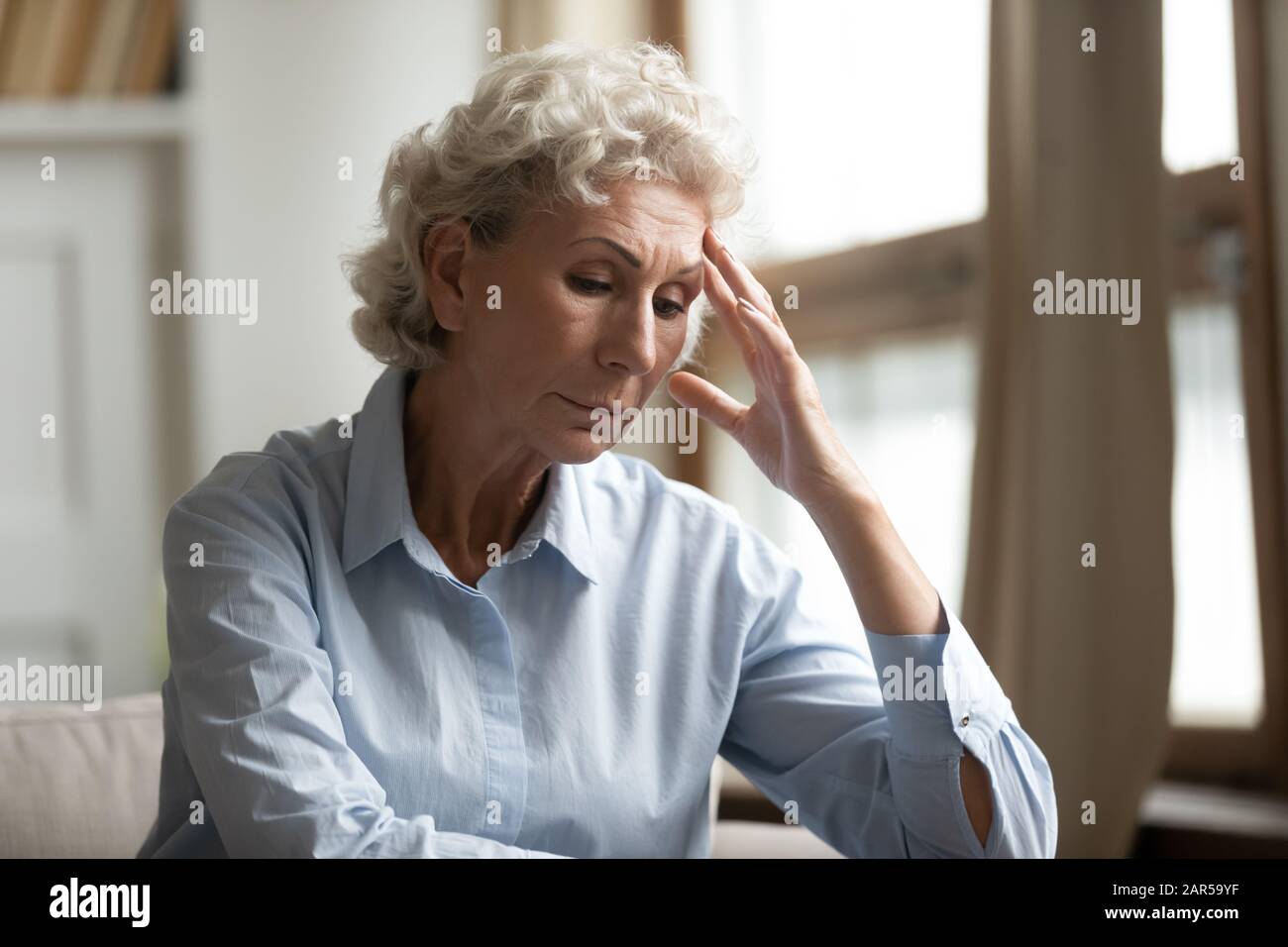 La grand-mère âgée et âgée stressée se sent mal, assise seule à la maison. Banque D'Images