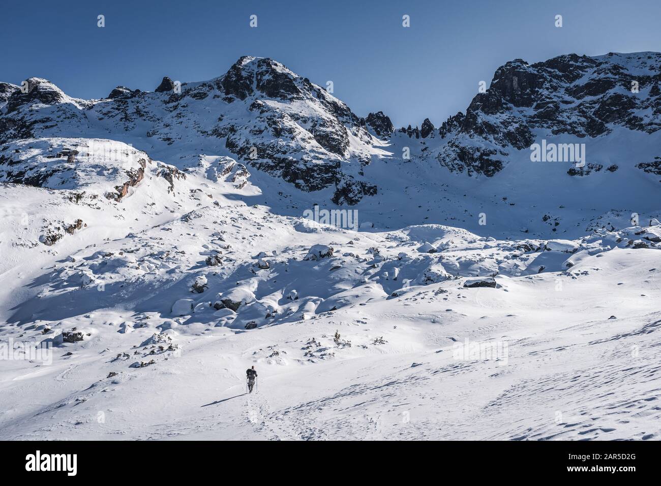 Randonneur seul en montagne d'hiver, devant les hauts sommets Banque D'Images