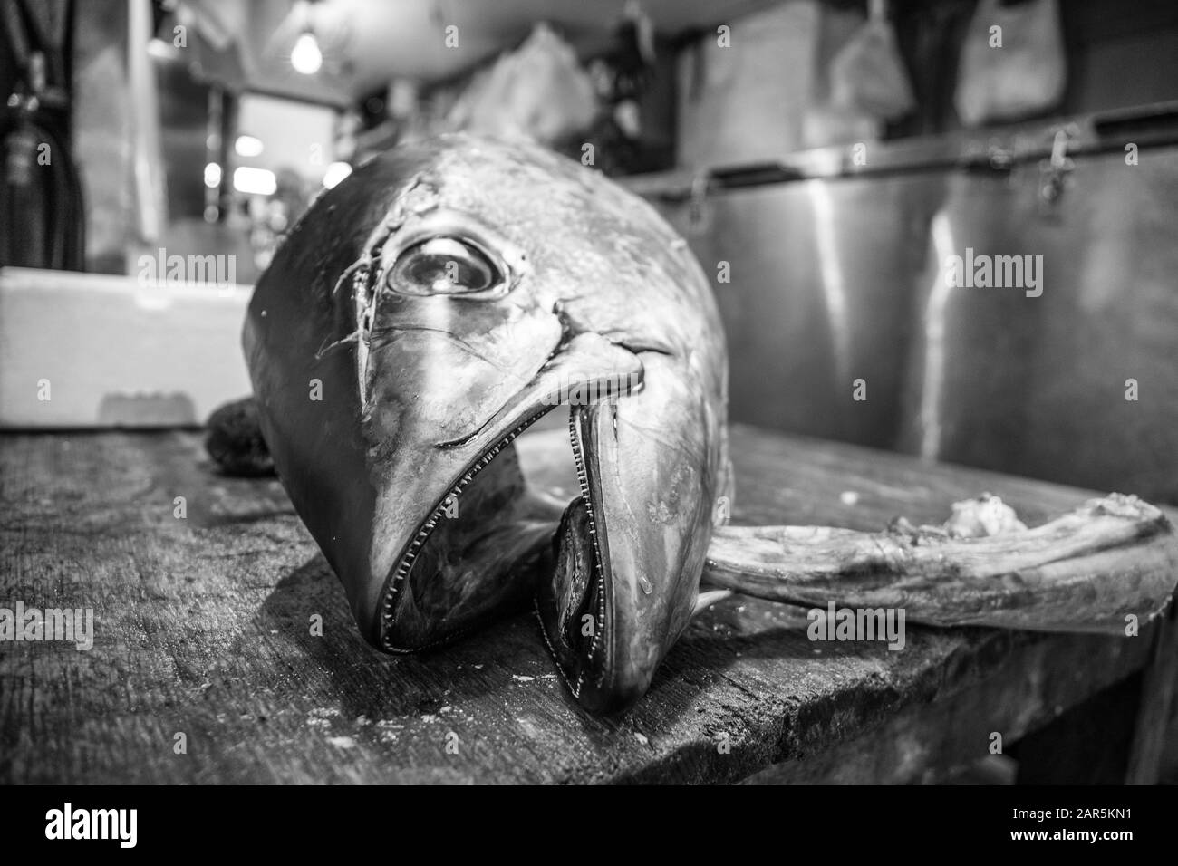 Cliché en échelle de gris d'un poisson mort sur une table en bois dans la cuisine Banque D'Images