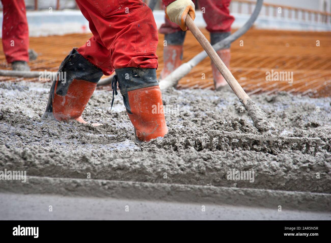 Groupe de travailleurs de la construction qui répandent le mélange de béton fraîchement coulé sur le pont Banque D'Images