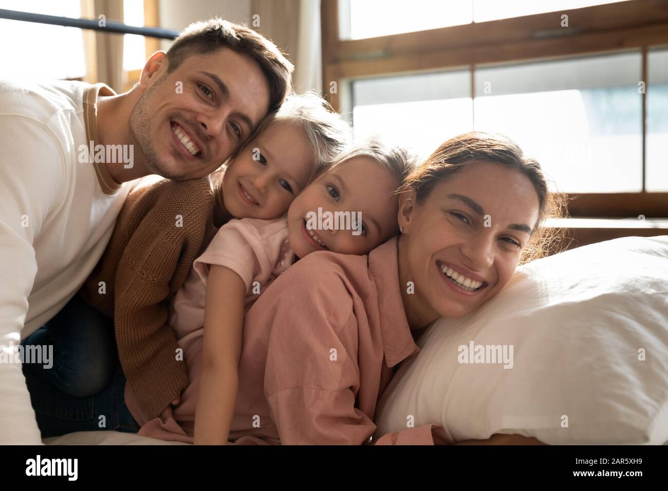 Portrait d'une jeune famille heureuse avec des enfants se relaxant dans la chambre Banque D'Images