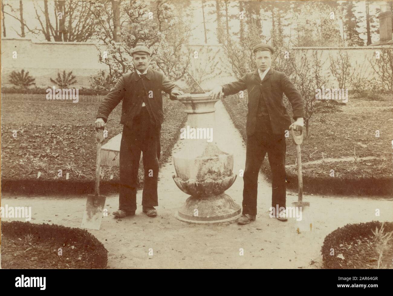 Les jardiniers édouardiens du groupe posent ensemble pour une photographie sur un chemin dans un jardin de cuisine bien entretenu et muré d'une grande maison de campagne, datée de 1909, au Royaume-Uni Banque D'Images