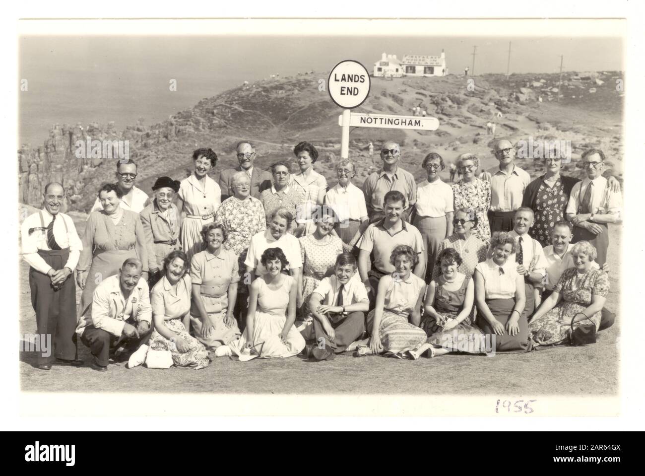 La photo commerciale de groupe de trippers de jour des années 1950 en vacances de Nottingham pose pour une photo à côté du célèbre signpost à Land's End, Cornwall, Royaume-Uni, daté d'août 1955 Banque D'Images