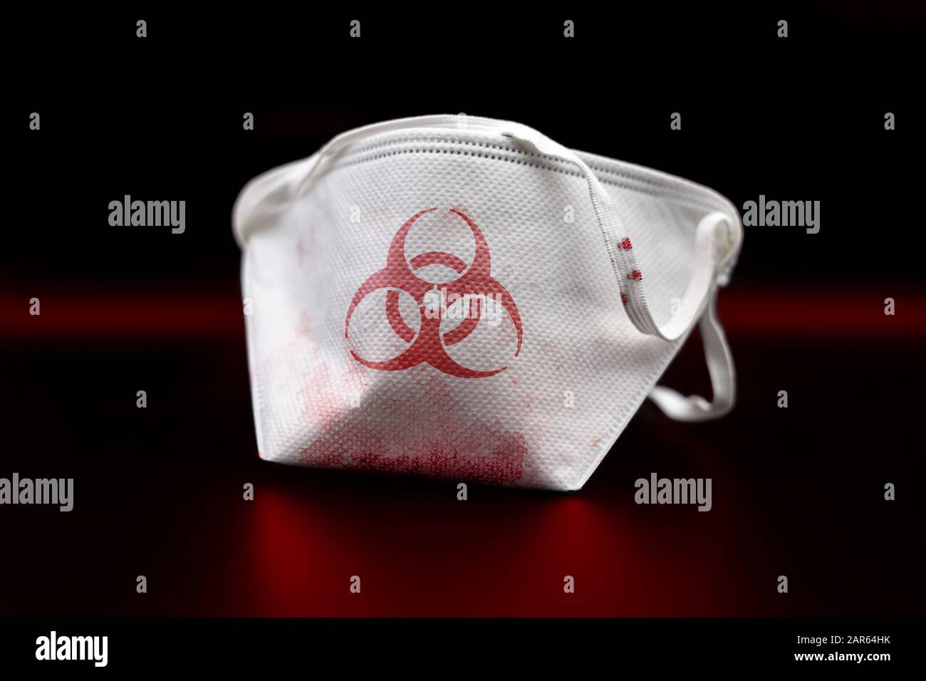 Masque de sécurité coloré par le sang avec un symbole de risque biologique, après une infection biologique (isolé sur fond noir). Banque D'Images