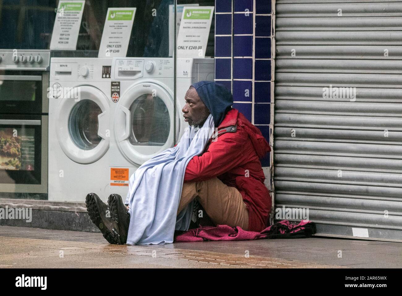 Un sans-abri est assis sur le pavé humide à l'extérieur du magasin de charité sans-abri Emmaus Preston. Emmaus Preston est un magasin indépendant de charité locale. Banque D'Images